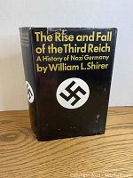 Front cover of the book showing title, author, and swastika symbol on black dust jacket with some edge wear.