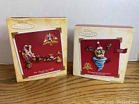 Two boxed Hallmark Keepsake Looney Tunes Christmas ornaments on wooden surface, box art visible.