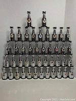 Full view of 44 silver and black mini Stanley Cups arranged in rows with NHL team logos visible