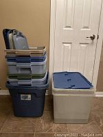 Stack of nine plastic storage containers: two large wheeled containers on the bottom and seven smaller containers on top and next to them. Four lids stacked separately on top of the smaller containers.