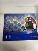 Photo showing full view of the coin set mounted on a blue branded display board with an athlete image and logos.