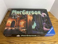 Closed game box showing MacGregor board game by Ravensburger with atmospheric castle artwork.