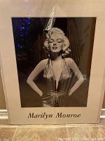 Black and white Marilyn Monroe poster still inside original cardboard cover, showing Marilyn in a dress with hands on hips, with text 'Marilyn Monroe' below.
