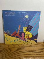 Front cover showing colorful abstract artwork with fireworks, bottle, guitar, and other shapes on blue background.