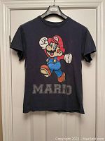 Front view of vintage black T-shirt with large colorful Mario graphic and 'MARIO' text