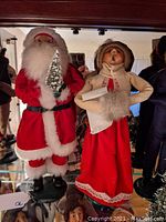 Santa Claus and Mrs. Claus figurines standing side by side on a shelf