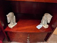 Wide view of two agate stone horsehead bookends placed on a wooden shelf, showing overall shape, size, and condition.