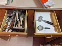 Two kitchen drawers shown open, displaying various kitchen utensils and cutlery items neatly arranged inside the drawers.