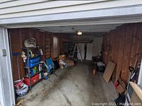 Wide view of garage interior showing shelving units, tools, boxes, and stored items.