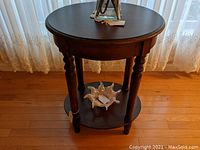 Front view of the dark solid wood round side table showing tabletops and turned legs.