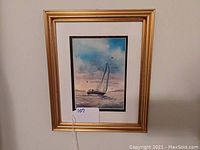 View of the full framed watercolor print depicting a sailboat on water with sky and birds, housed in gilt frame.
