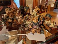 Group photo showing nine Boyds Bears figurines arranged on a glass surface including two bears with telephones and a small boat model.