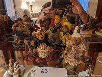 Group of seven seated Boyds Bears resin figurines on mirrored surface, clearly showing detailed hand-painted decorations and themes such as birthday and welcome signs.