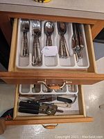 Top drawer with JA Henckels flatware consisting of forks, spoons, and knives in organizer tray.