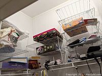 Photo showing multiple wire shelves with various stored items including books, a colorful textile item, a boxed furniture mover, and small electronic accessories.