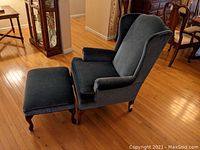 Blue velvet upholstered chair and footstool set, showing side angle with chair and footstool resting on wooden floor.