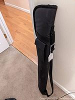 Full view of soft black carry case standing upright, showing shape and condition.