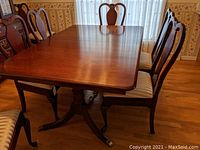 Solid cherry wood dining table with two leaves inserted on pedestal base