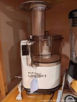 Full view of Moulinex Regal La Machine II food processor unit with clear plastic work bowl and feeding tube fit on a base with power cord.