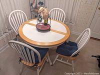 Four wooden Windsor chairs around a white and natural wood table with blue seat cushions tied on each chair. Image shows full set and condition of chairs.