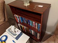 Full view of the solid wood bookcase with books on middle and lower shelves, and a decorative lamp on top.
