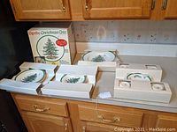 Entire 20-piece set displayed on counter in original boxes showing plates, cups, and saucers with Spode Christmas Tree design.