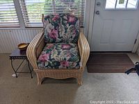 Front view of the wicker and rattan chair with floral cushions positioned near a window and door.