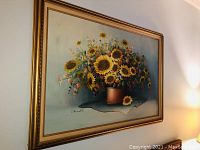 View of the full framed oil painting showing the bouquet of sunflowers in a copper pot on blue fabric.