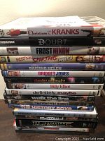 Stack of 15 DVDs showing spines with titles including Christmas with the Kranks, Doubt, Frost/Nixon, Meet the Spartans (Unrated), Raising Helen, Bridget Jones: The Edge of Reason, Slumdog Millionaire, and others.