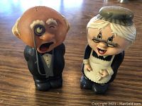 Front view of ceramic sneezing man and bless you woman salt and pepper shakers on wooden surface