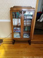 Front view of solid oak bookcase showing two glass-paneled doors and three shelves with books