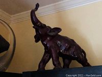 Full side angle of the solid rosewood elephant sculpture showing its raised trunk and polished finish.