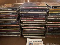 Photo showing a variety of compact discs grouped in four stacks, featuring compilation albums and individual artist CDs.