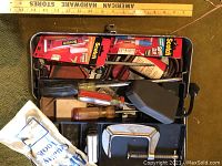 Top-down photo of an open vintage metal toolbox showing various USA made tools including several screwdrivers and clamps, rolls of adhesive tape mostly Scotch brand, a small black case, and other hand tools.