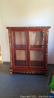 Front view of red lacquered wood cabinet with gilt carvings and dragon feet