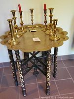 Full view of scalloped brass-top table with eight candlestick holders