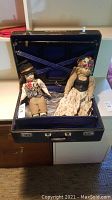 Antique suitcase open showing two plush dolls inside