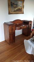 Front view of antique mahogany sideboard showing curved center with two drawers and side cabinets with doors and knobs. Note one knob missing.