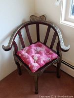 Front angled view of corner chair with pink cushion showing curved back, slatted sides, metal overlay and cushion (cushion not included)