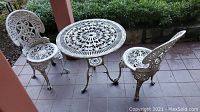 Front view of round table flanked by two matching chairs on tiled patio