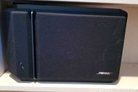 Front view of one black Bose 101 Series IV speaker showing black fabric grille and Bose logo in bottom right corner.