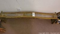 Full length front view of brass fireplace hearth fender leaning against wall.