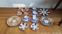 Full display of assorted china: tea cups with matching saucers and decorative small plates arranged on wooden surface.