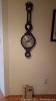 Full view of wall-mounted barometer with book placed beneath