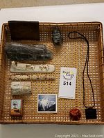 Overview of the collection of soapstone carvings and additional items displayed in a woven tray including a wallet and pendants.