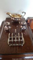 Group shot showing gravy boat, two pepper shakers, and toast rack on wooden surface