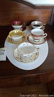 Overview of all five assorted tea cup and saucer sets arranged on wooden surface