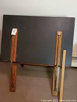 Front view of closed portfolio case on built-in tripod stand showing black cover and wooden supports