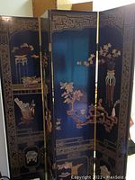 Full view of four-panel black lacquer folding screen with carved and inlaid stone floral and decorative motifs