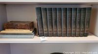 Close-up view of the Wise & Co Little Journeys set spines, volumes I to XI with visible wear and fading